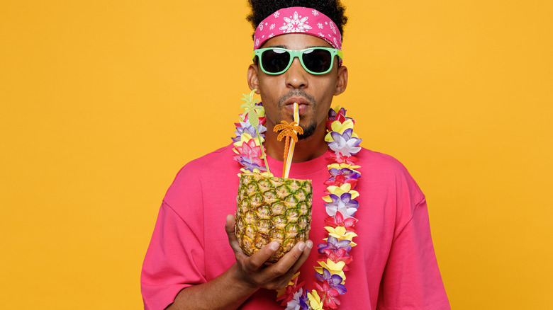 Tourist with a lei sipping on a pineapple drink