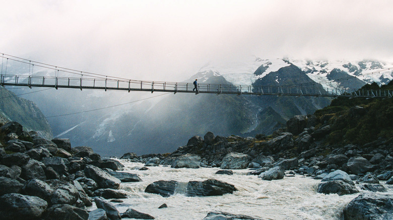 hiker on suspension bridge in mountains