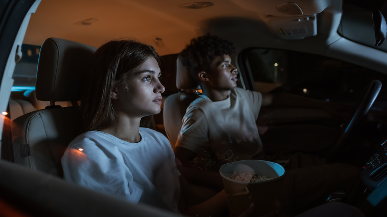 couple eating popcorn in car