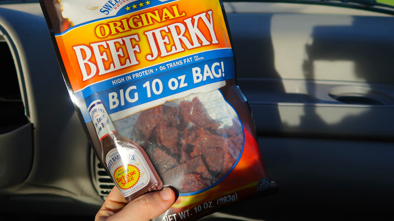 Hand holding jerky inside car