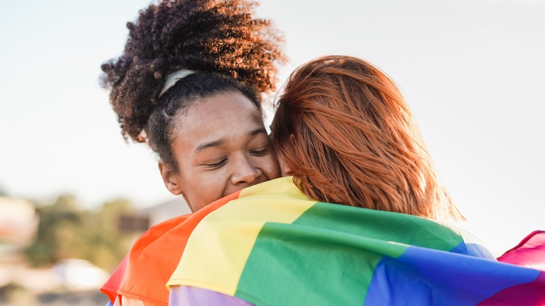 queer couple smiling with rainbow flag