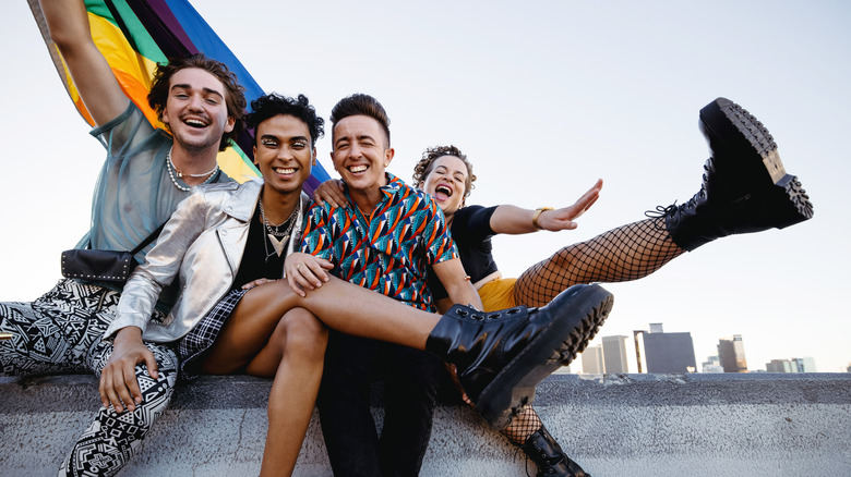 queer people smiling with rainbow flag