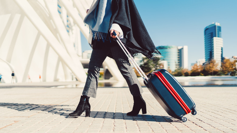 Woman rolling a suitcase outside