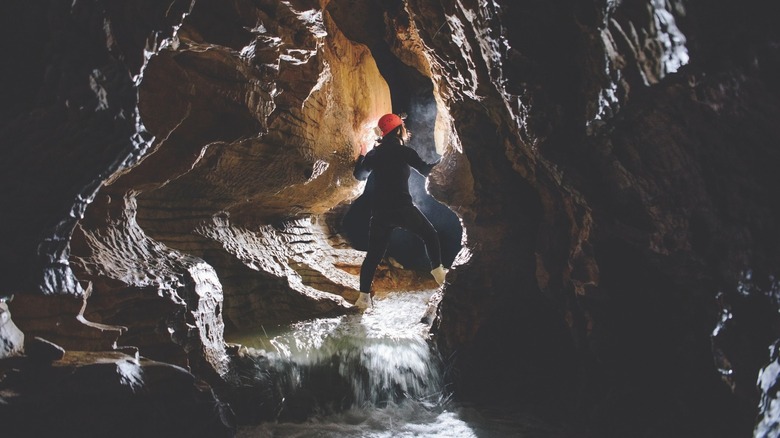 Caver steps over underground creek