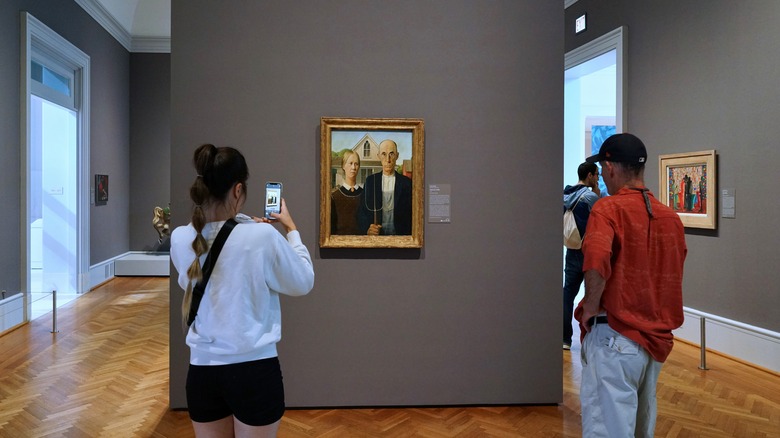 Visitors photograph a painting