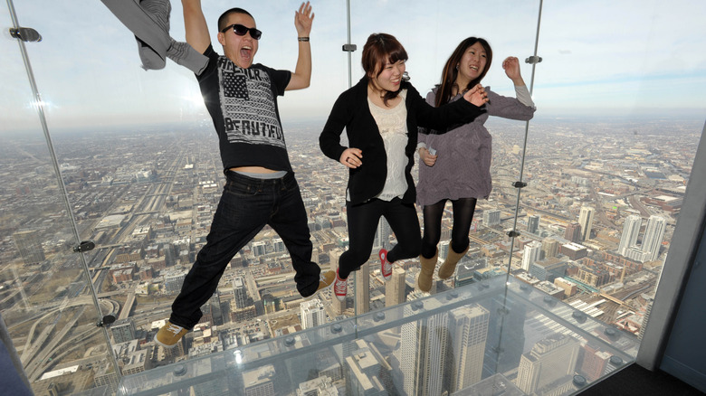 Three people jumping on skyscraper platform