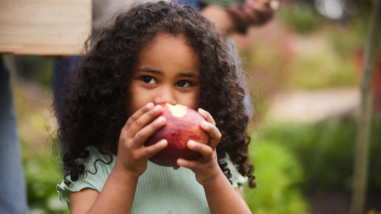 Child biting into an apple