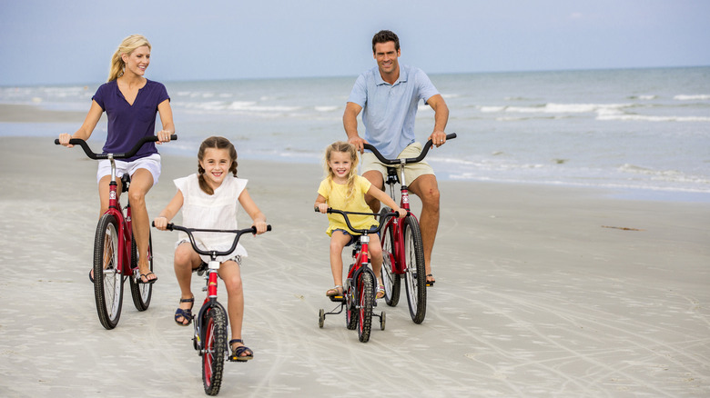 A family riding bikes on the beach at The Sea Pines Resort