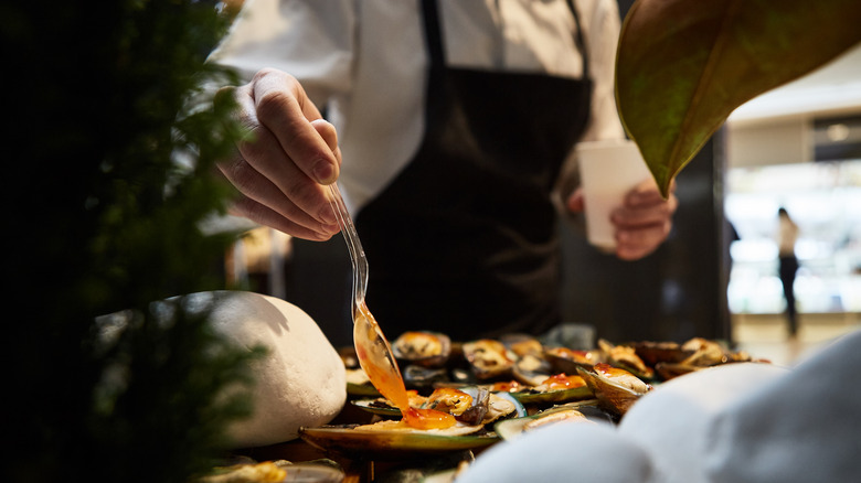 Waiter adding sauce to a seafood dish