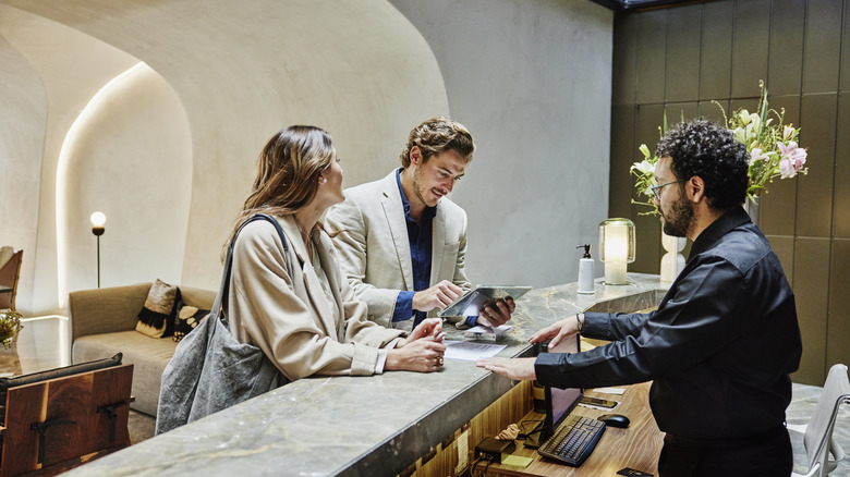 A couple at a hotel front desk.