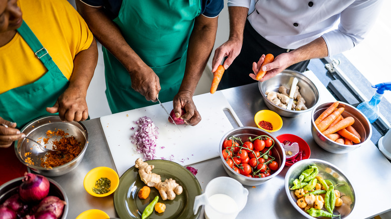 three people prepping countertop ingredients