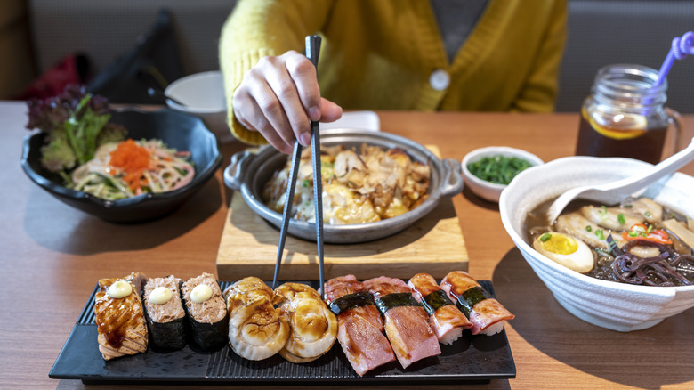 Person eating various Japanese foods with chopsticks