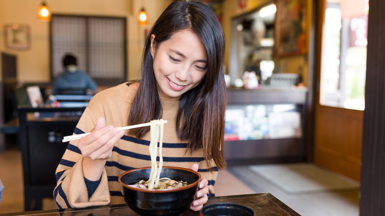 woman eating udon in restaurant