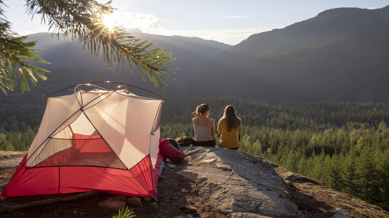 Girls watch sunset near tent