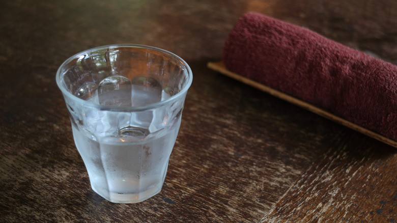 Half-empty thimble-sized water glass Japan and moist hand towel