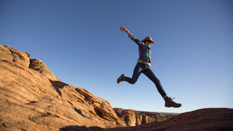 Person jumping between sandstone rock formations