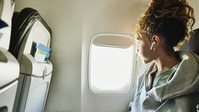 plane passenger with earbuds looking out window