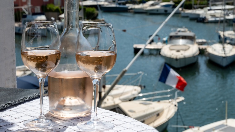 Glasses of rosé wine on table near a harbor