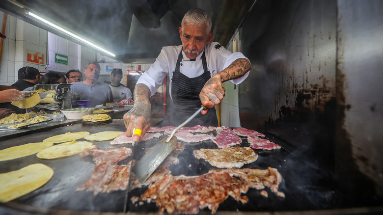 A man cooks tacos on in a small shop in Mexico City