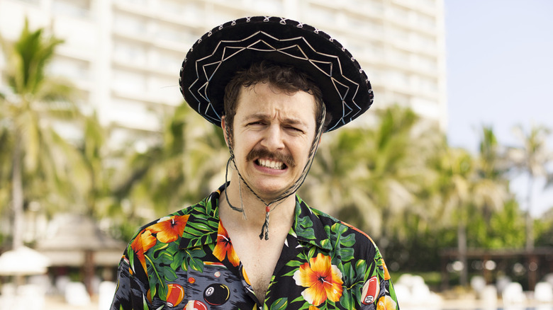 A tourist wears a sombrero and floral print shirt