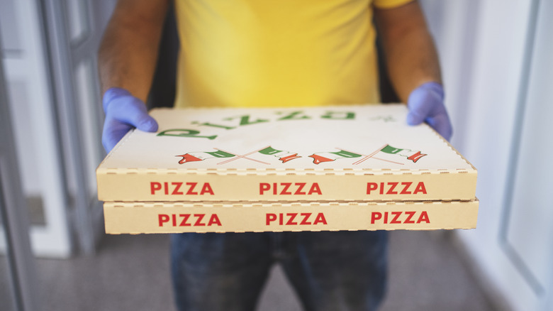 Pizza delivery person holding boxes