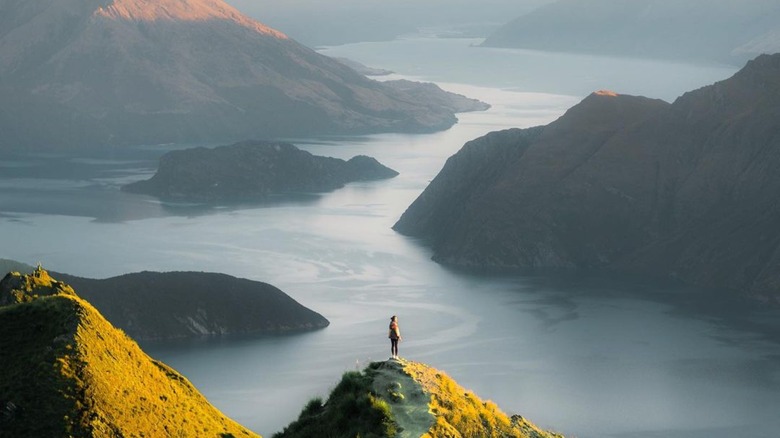 hiker on peak looking over new zealand landscape