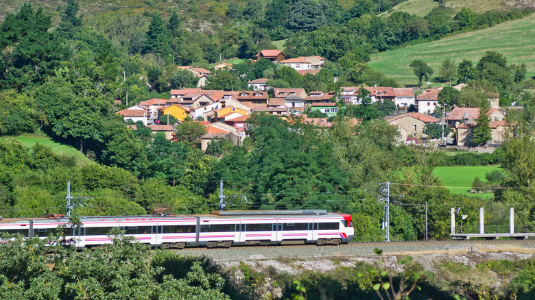 A modern train passing near a village in Northern Spain