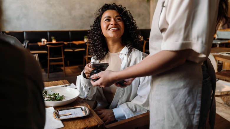 Smiling traveler paying for dinner