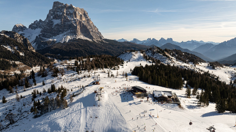 Skiers gliding beneath towering crag of Monte Civetta in Italy