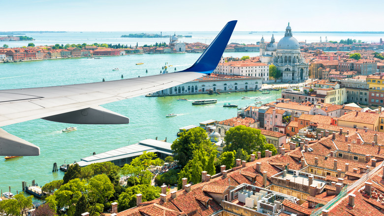 Wing of plane over canals and city of Venice