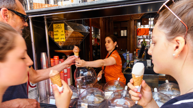 Shopkeeper serving gelato to customers