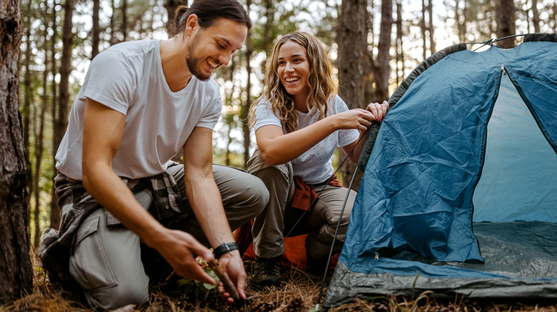 Couple setting up camping tent