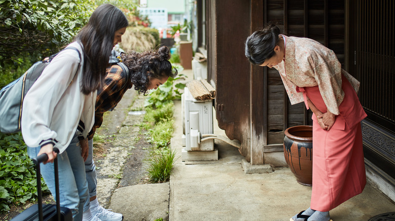 Travelers bowing before Japanese inn keeper