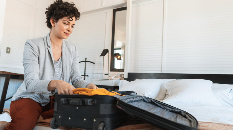 woman packing suitcase on bed