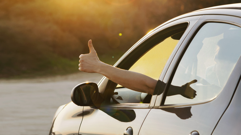 a thumbs up sticking out of a car window