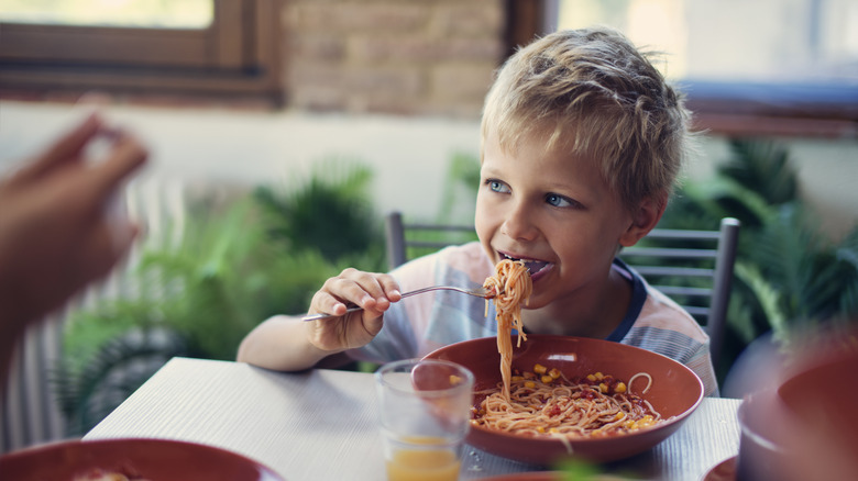 Young boy eats spaghetti