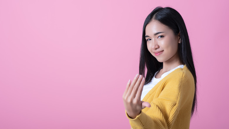 Young woman beckons with hand