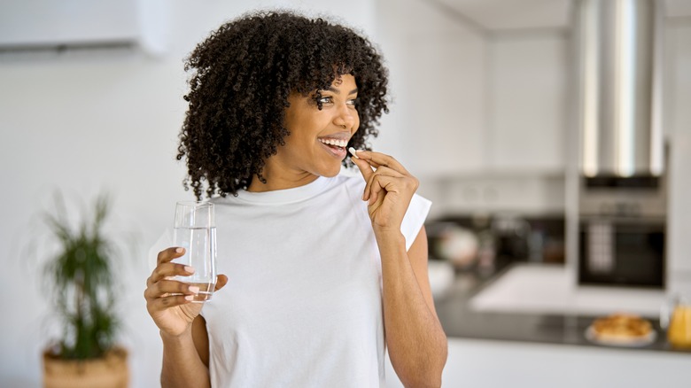 woman taking pill with water