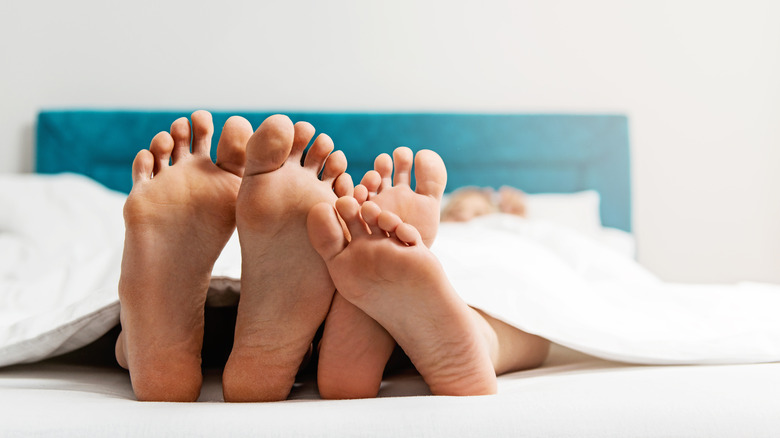 two people's feet in bed