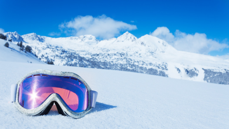 goggles on snow against blue sky and clouds