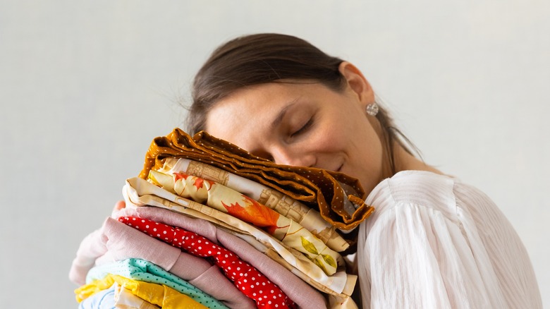 Woman holding stack of folded clothes.