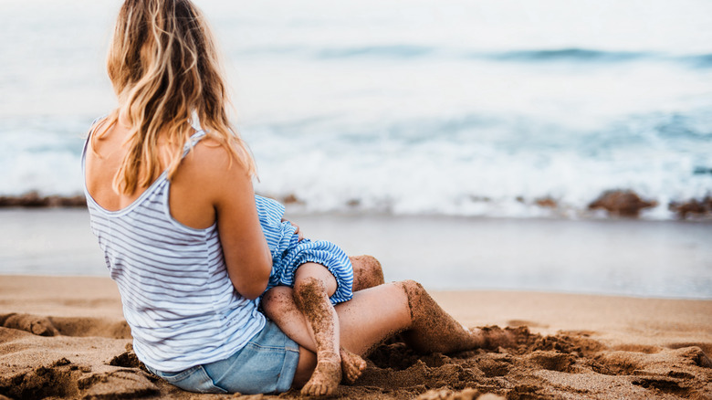 mother breastfeeding child on beach