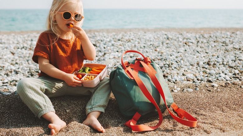 toddler on beach with snacks