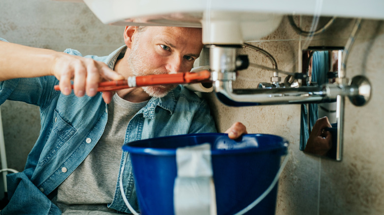 A man fixing a broken pipe