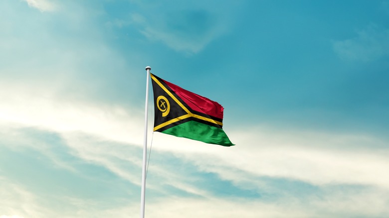 Vanuatu national flag flying with blue sky.