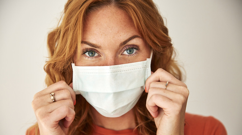 A woman puts on a face mask