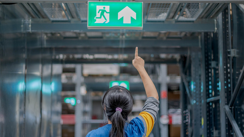 woman pointing to exit sign