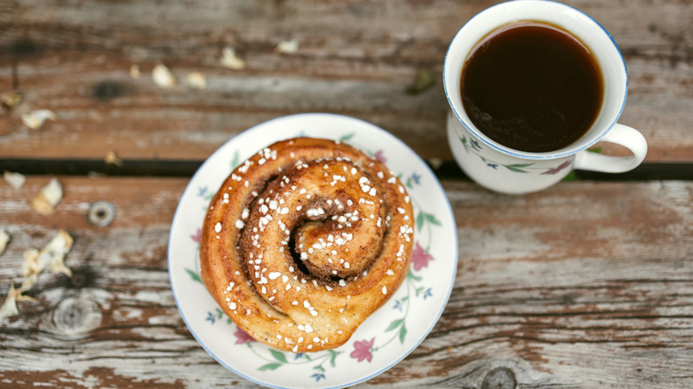 Coffee and a cinnamon roll on a wooden table.