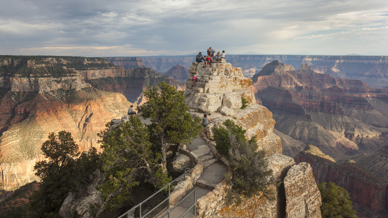 Hikers atop rock formations looking across the Grand Canyon from Bright Angel Point North Rim