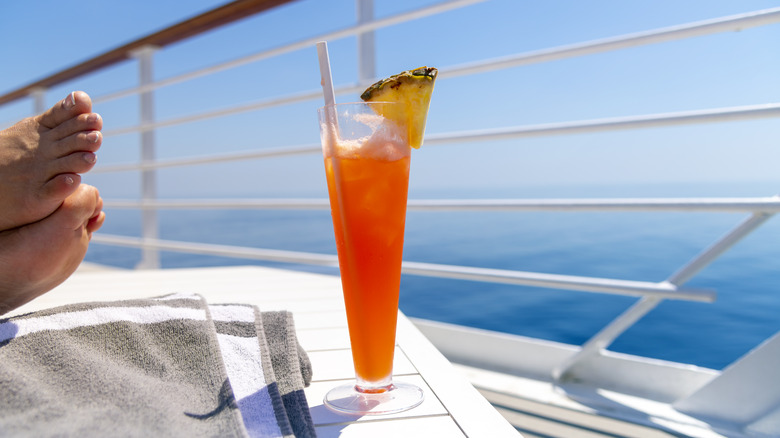 Bare feet resting by a drink on a cruise